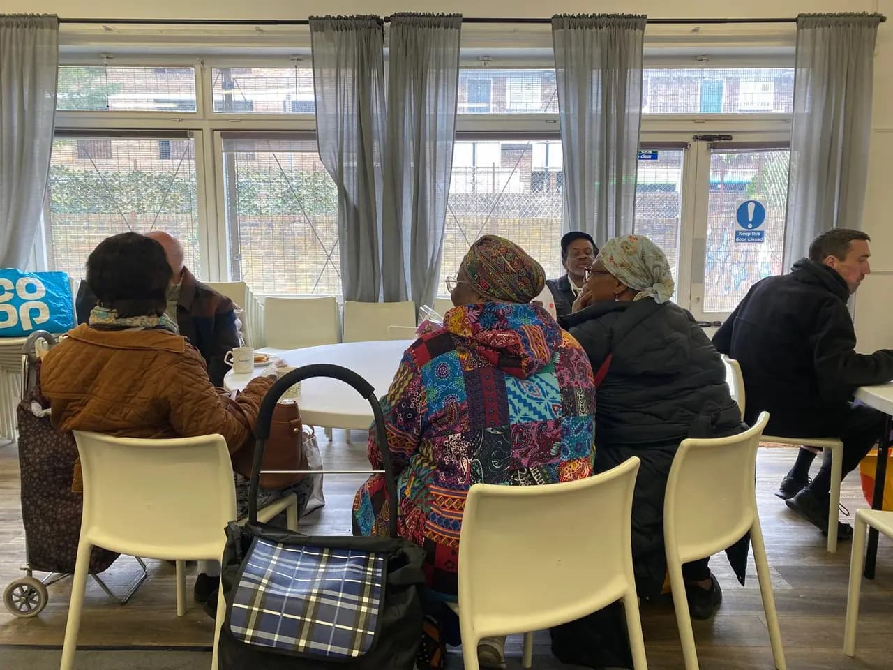 Adults meeting around tables at Deronda Community Hall