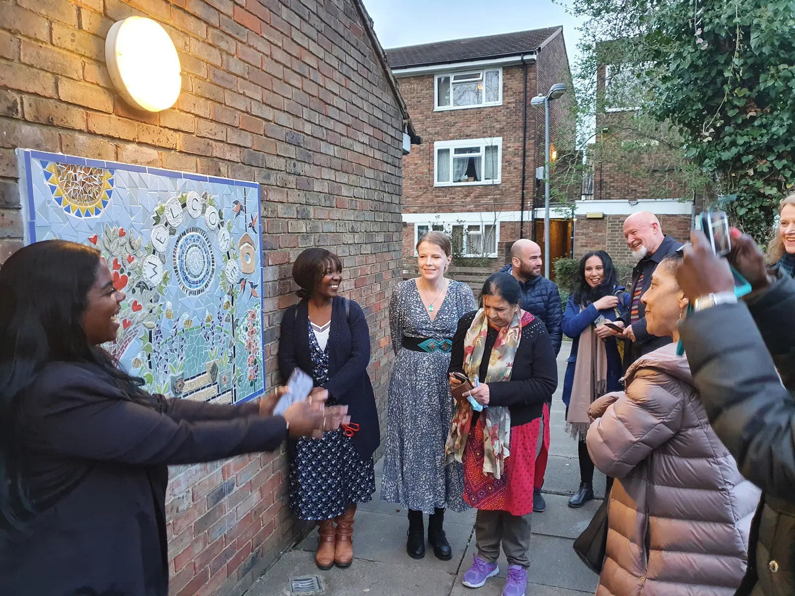 Community members and partners gathered beside the completed garden mosaic